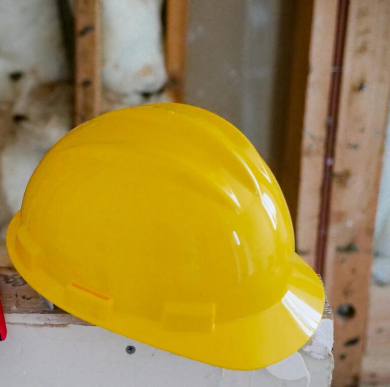 Close Up Photo of Yellow Hardhat and Red Protective Gloves