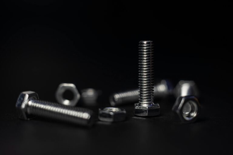 Detailed close-up of metal screws and nuts with a dark background highlighting textures and shapes.